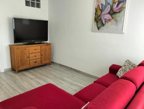 a red couch in a living room with a flat screen tv at Casa Alla Veduta in Trento