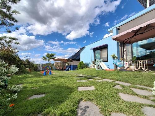 a yard with grass and stones in front of a house at Yeoncheon Jjongi and Mary Pet Friendly Pension in Yeoncheon