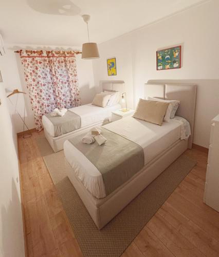 a bedroom with two beds and a table with a lamp at Ribeiro house in Lourinhã