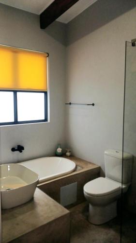 a bathroom with a tub and a toilet and a sink at OppiStoep in Clarens