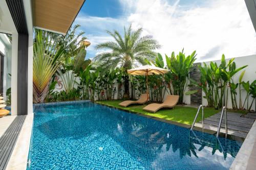 a swimming pool with two chairs and an umbrella at Sunny Day Dream Villa - Nai Yang Beach in Thalang