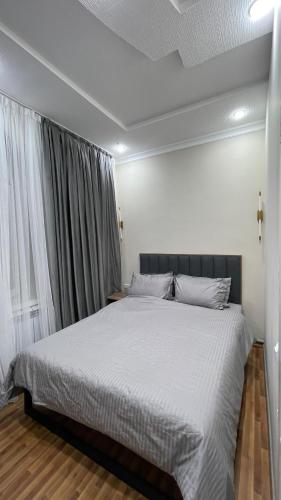 a bedroom with a large bed with white sheets at Boston in Osh
