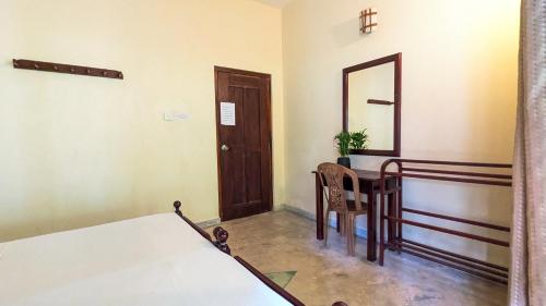 a room with a bed and a table and a mirror at Gishi's Happy Stay - Galle in Galle