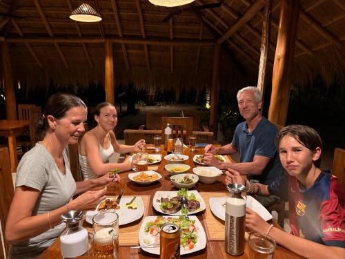 a group of people sitting around a table eating food at Agro Village Resort , Kalpitiya in Kalpitiya