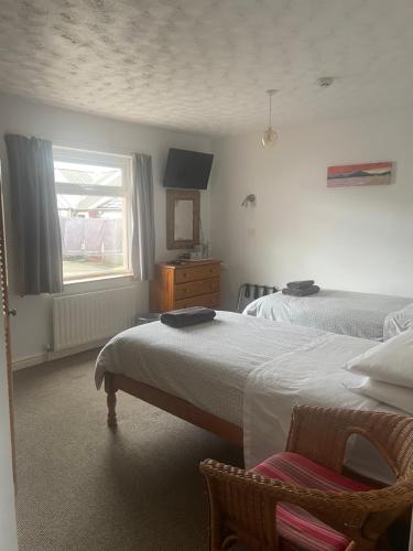 a bedroom with two beds and a window at Carnside Guest House in Bushmills