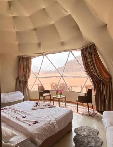 a bedroom with a bed and a large window at Wadi Rum Luxurious Camp View in Wadi Rum