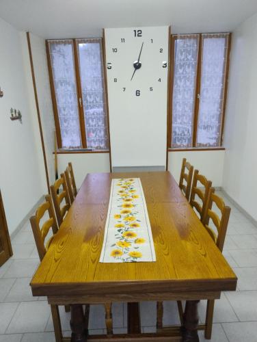 a dining room table with a clock on the wall at gite morvan in Lormes