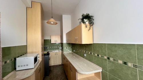 a kitchen with wooden cabinets and green tiles at Apartament pod Góralką in Polanica-Zdrój