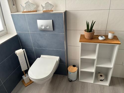 a bathroom with a toilet and a blue tiled wall at Ferienwohnung -Diemelaue- in Warburg