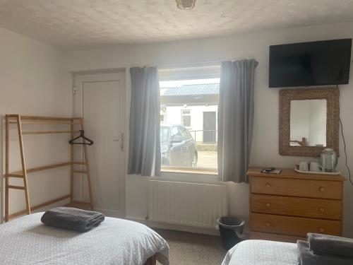 a bedroom with a bed and a window with a mirror at Carnside Guest House in Bushmills