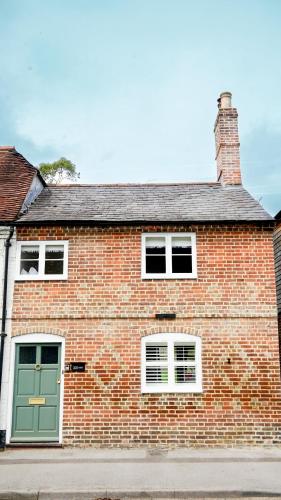 a brick house with a green door on a street at Hazelbury Cottage in Wilton
