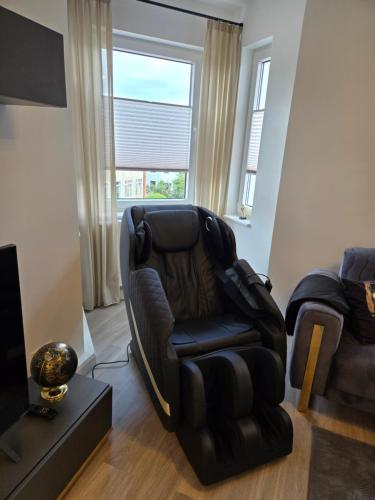 ein Wohnzimmer mit einem schwarzen Stuhl und einem TV in der Unterkunft City Apartment in Bremen