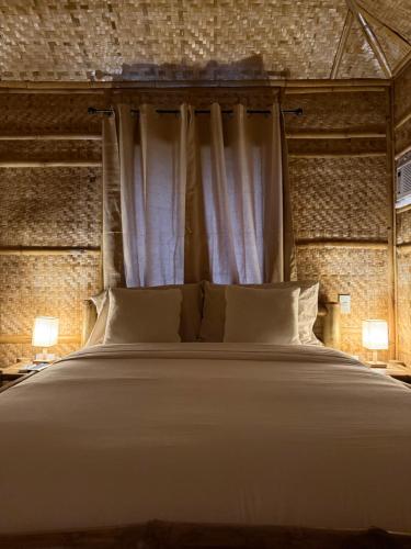 a bedroom with a large white bed with two lamps at The Bamboo villas 2 in Pooc