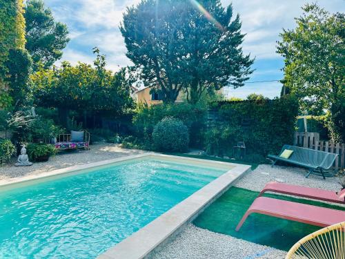 a swimming pool with a table and a bench next to it at Le Jardin in LʼIsle-sur-la-Sorgue
