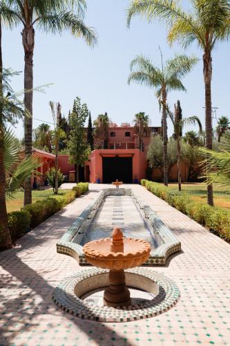 a fountain in the middle of a courtyard with palm trees at Villa Marrakchia - Palais d'hôtes & spa in Marrakech