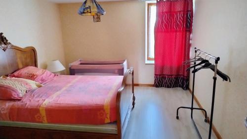 ein Schlafzimmer mit einem Bett und einem roten Vorhang in der Unterkunft La vie en rose in Courpière