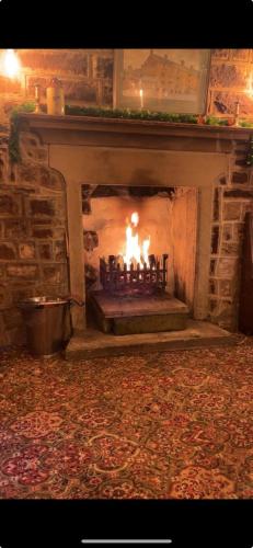 a stone fireplace with a fire in it at Jug and glass in Highpeak Junction