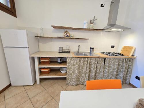 a kitchen with a sink and a white refrigerator at La casa di Lino in Volta Mantovana