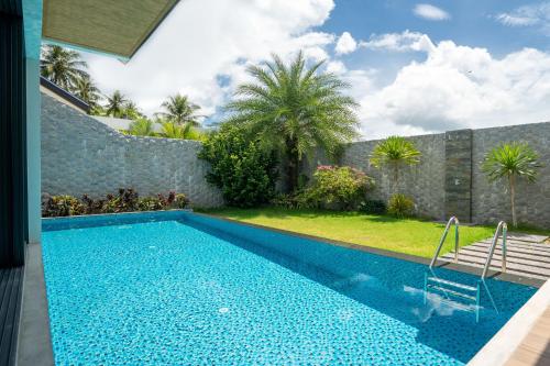a swimming pool in a yard with a stone wall at Blue Coral Luxury Villa - Tropical Modern Living in Phuket