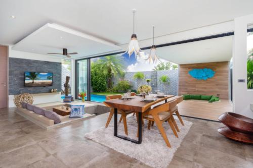 a dining room with a table and a couch at Blue Coral Luxury Villa - Tropical Modern Living in Phuket