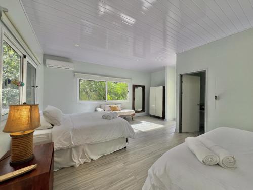 a white bedroom with two beds and a window at Selvatica - Superior Double Room in Punta Uva