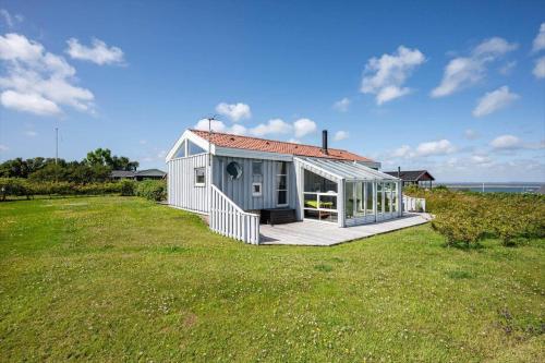 a small house on a lawn with the ocean in the background at G608-Lemvig-Gyvelvej-8 in Lemvig