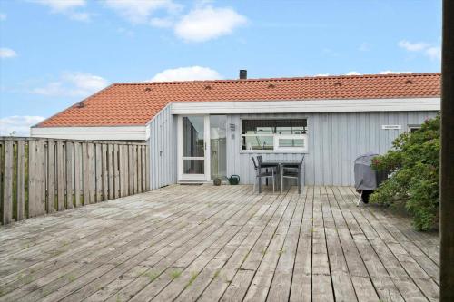 a house with a wooden deck with a table at G608-Lemvig-Gyvelvej-8 in Lemvig