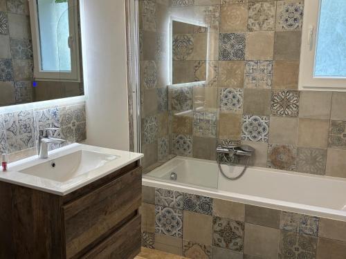 Mauzac-et-Grand-CastangにあるLa Pierre dorée - Love Room - Jacuzzi privatifの洗面台と浴槽のあるバスルーム