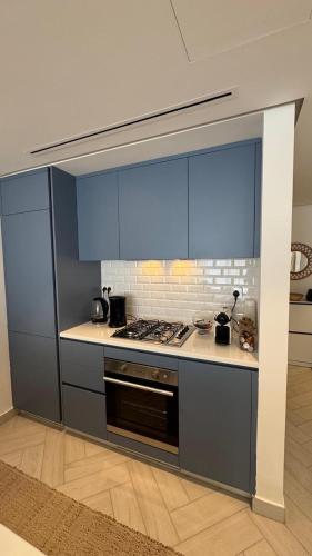 een keuken met blauwe kastjes en een fornuis bij Ayla-Azure in Aqaba