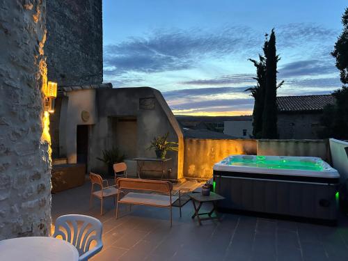 a patio with a hot tub and a table and chairs at Belles chambres et SPA, en pleine nature in Cournonsec