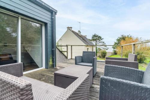 a patio with chairs and tables on a deck at Maison lumineuse à 50m de la mer idéale en famille in Riantec