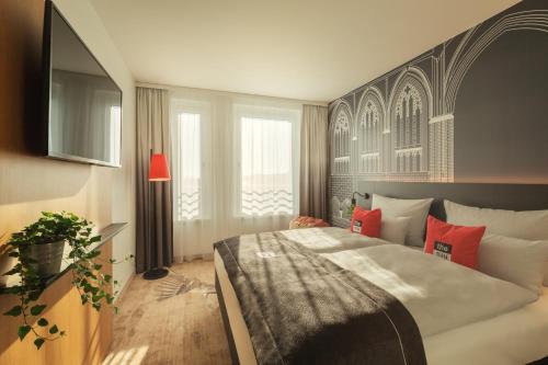 a bedroom with a large bed with red pillows at Holiday Inn - the niu, Sparrow Regensburg by IHG in Regensburg