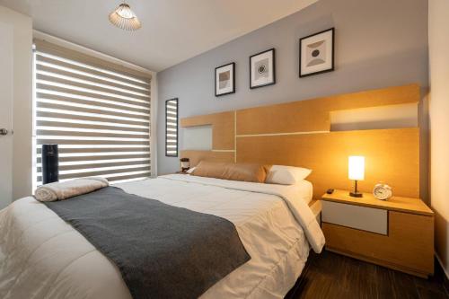 a bedroom with a large bed and a night stand with a lamp at Departamento cerca de Estadio GNP y Aeropuerto in Mexico City