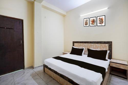 1 dormitorio con 1 cama blanca grande con almohadas negras en Hotel O Vip Stay Inn, en Ghaziabad