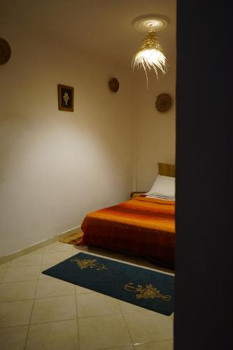 a bedroom with a bed and a chandelier at Bright Wave Surfhouse in Tamraght Ouzdar