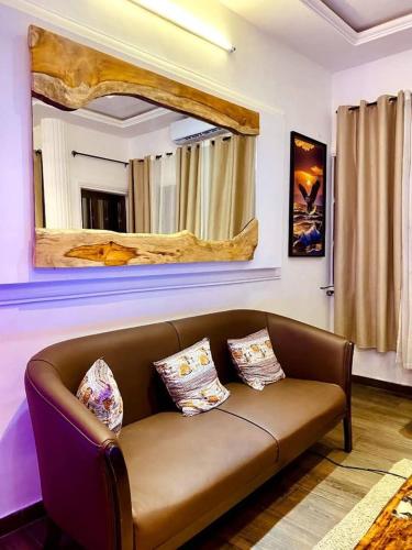 a living room with a brown couch and a mirror at 2 chambre 1 Selon a Cotonou stade in Cotonou