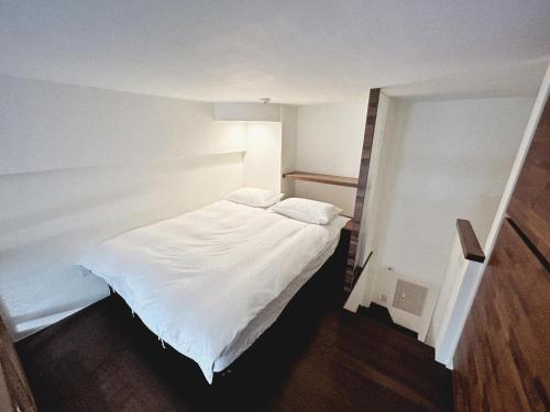 a small bedroom with a white bed in it at Rihe Hot spring B&B in Jiaoxi