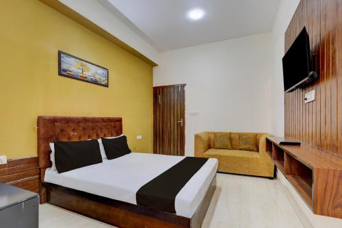 ein Schlafzimmer mit einem Bett, einem TV und einem Stuhl in der Unterkunft Hotel O The Grand Luxury in Noida