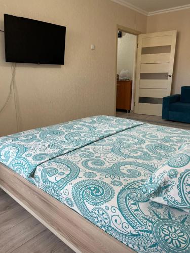 a bedroom with a bed with a television on the wall at Авангард 4-12 in Atyraū