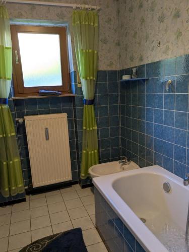 a blue tiled bathroom with a tub and a window at Villa Viola 