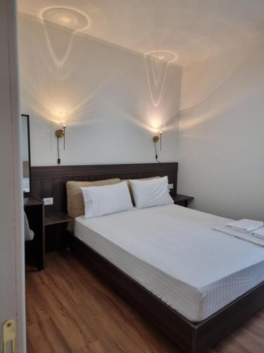 a bedroom with a bed with white sheets and two lights at KC Apartments 3 in Berat