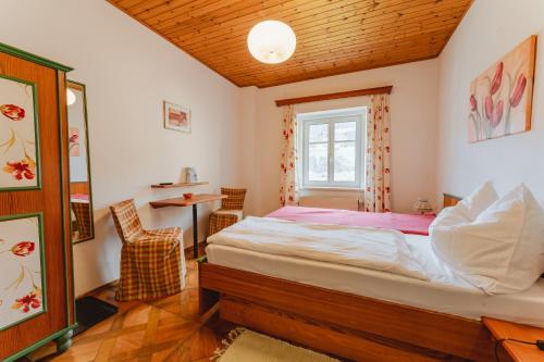 a bedroom with a bed and a table and a window at Frühstückspension Zippo in Greifenburg