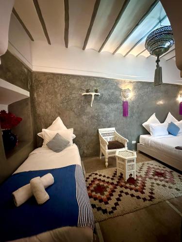 a bedroom with two beds and a chair in it at Riad Green Palm in Marrakech