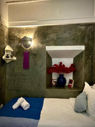 a bedroom with a bed and a vase with red flowers at Riad Green Palm in Marrakech
