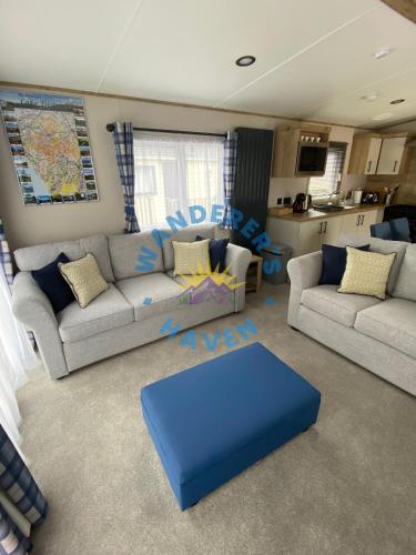 a living room with a couch and a blue ottoman at Wanderers Haven, Brigham, Cockermouth, Cumbria in Brigham