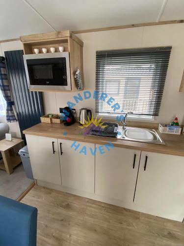 a kitchen with a sink and a microwave at Wanderers Haven, Brigham, Cockermouth, Cumbria in Brigham