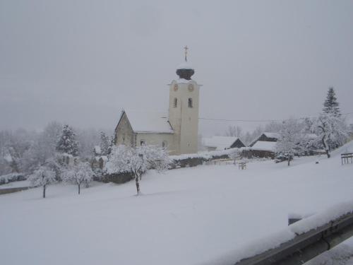 a church in the snow with snow covered trees at Frühstückspension Zippo in Greifenburg