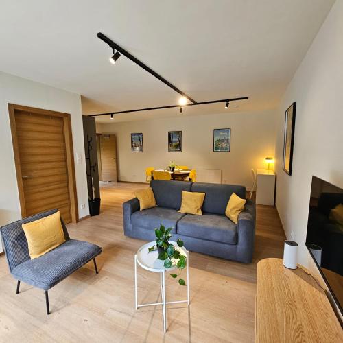 a living room with a blue couch and a table at Le gîte de Hourpes in Thuin