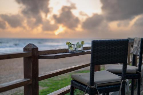 a table with two chairs and glasses on the beach at Villa 46 in Hikkaduwa