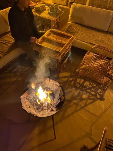 a man sitting in front of a fire in a living room at Soléi Salt in siwa oasis